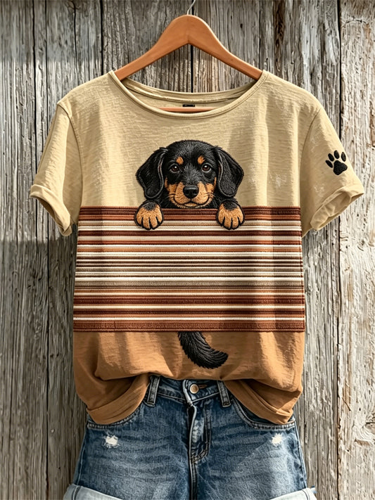 Camiseta de manga corta para mujer con estampado en bloques de colores y diseño de perro salchicha asomándose junto a huellas de patas